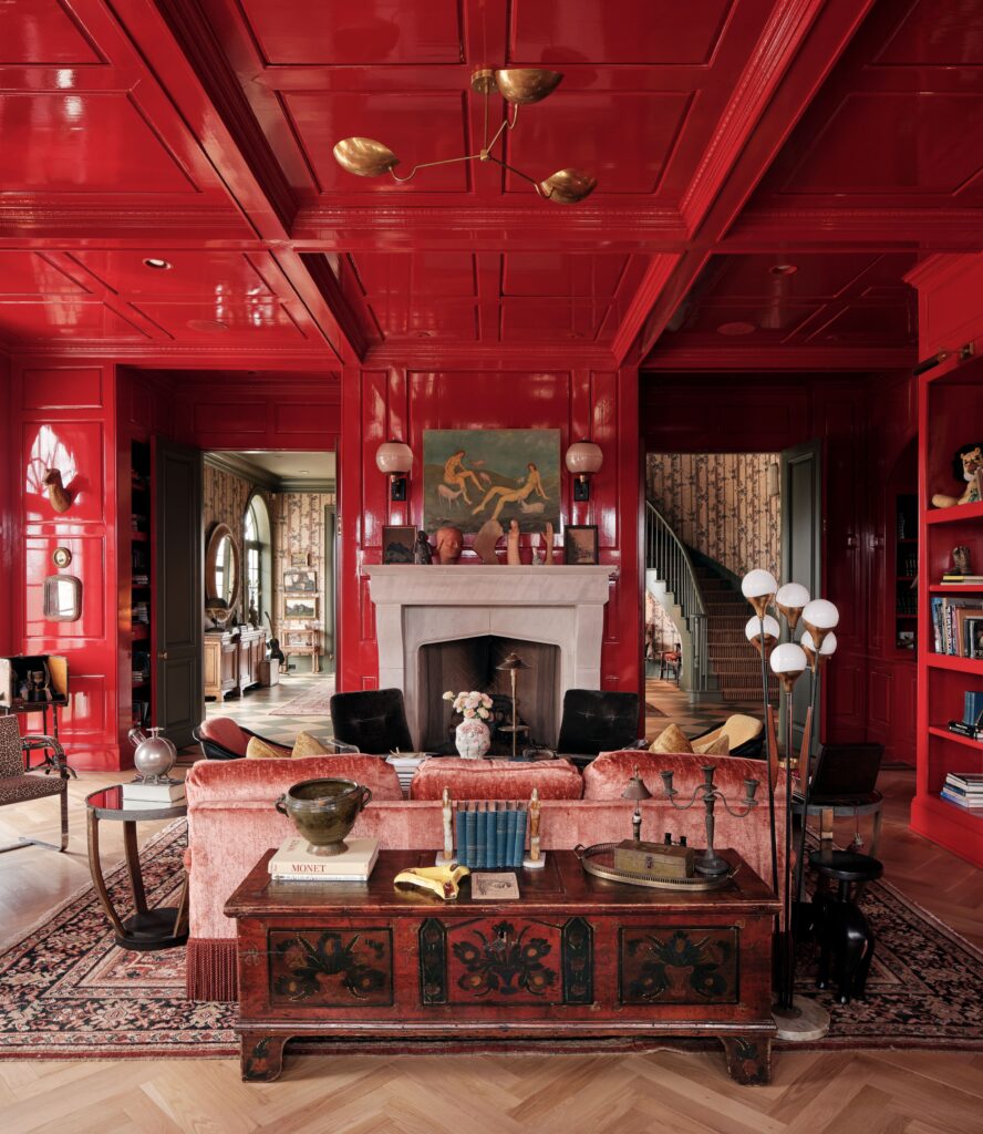 光滑的红色墙壁和红色格子天花板粉红色沙发对面白色壁炉架内衬雕塑和框架......