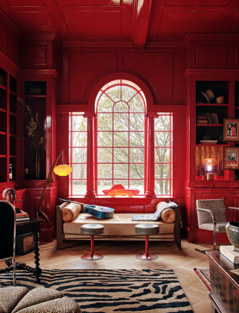 光滑的红色格子天花板和墙壁帕拉第奥式窗户，柱子框架着红色玻璃汽车雕塑米色沙发床......